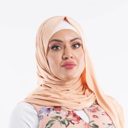 Woman wearing a warm camel premium jersey hijab styled with an elegant front drape, showing the soft and opaque fabric.