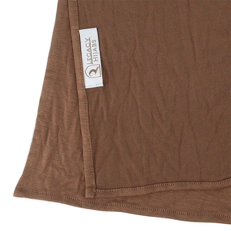Neatly folded dark mocha premium jersey hijab on a flat surface, showcasing its rich coffee-brown tone and medium-weight fabric.