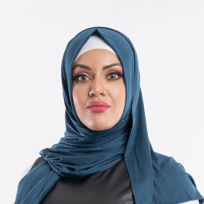 Woman wearing a deep dark teal premium jersey hijab styled with a front drape, demonstrating the smooth and opaque fabric.
