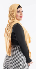 Side profile of a woman wearing the mustard yellow premium jersey hijab, highlighting the comfortable, pin-free stretch fit.