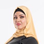 Woman wearing a warm mustard yellow premium jersey hijab styled with a front drape, demonstrating the soft and opaque fabric.