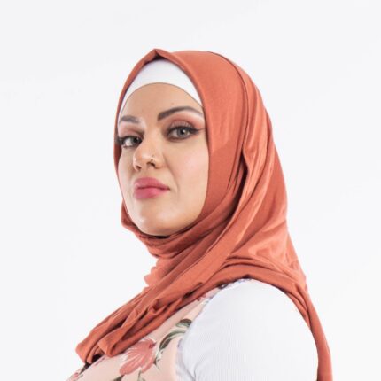Woman wearing a warm sienna premium jersey hijab styled with an elegant front drape, demonstrating the smooth and opaque fabric.