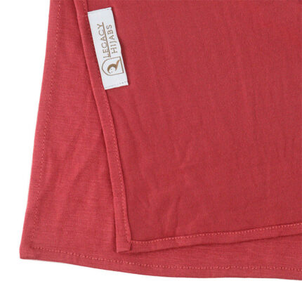 Neatly folded watermelon premium jersey hijab on a flat surface, showcasing its bright pinkish-red tone and medium-weight fabric.