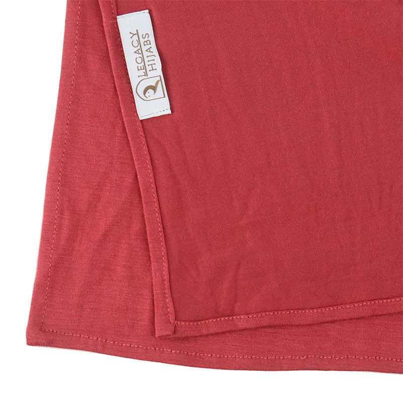 Neatly folded watermelon premium jersey hijab on a flat surface, showcasing its bright pinkish-red tone and medium-weight fabric.